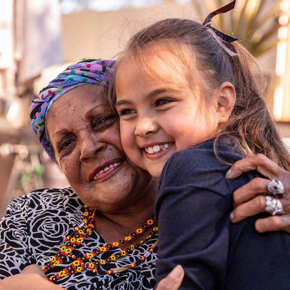 elderly indigenous women embracing a young indigenous girl