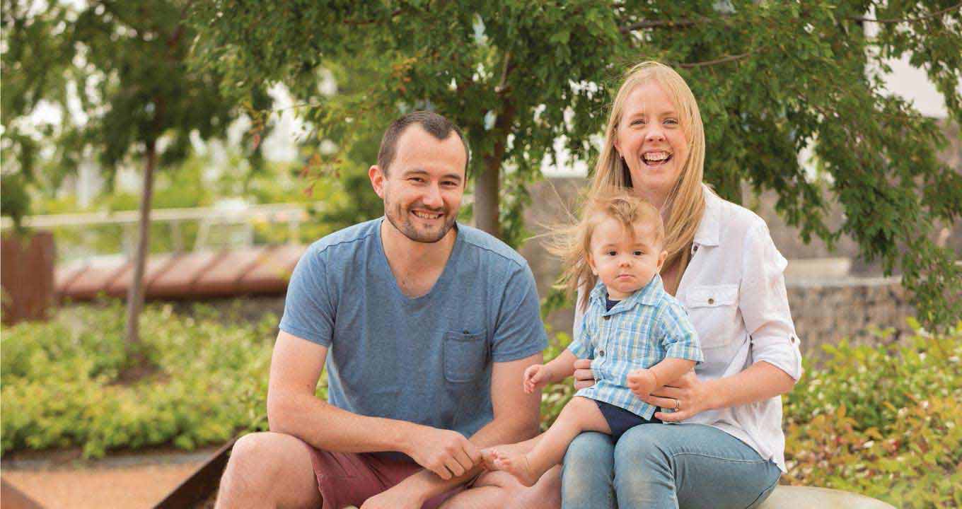 Young parents sitting with child in park
