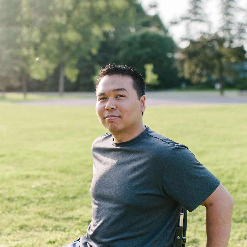Young man in wheelchair in park looking at camera