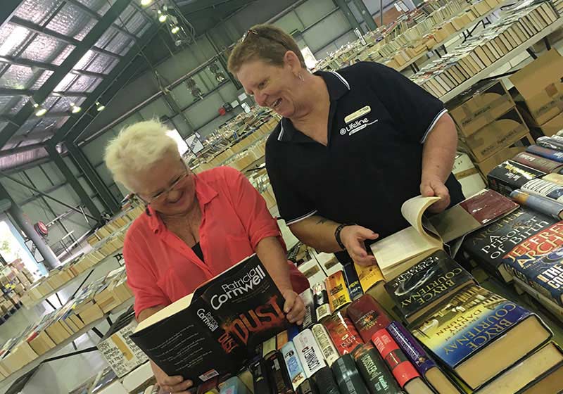 two ladies smiling in a warehouse filled with books