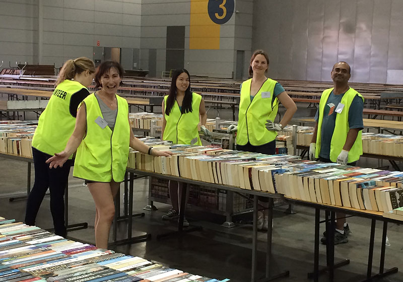 staff member in bright yellow vest working in a warehouse filled with books