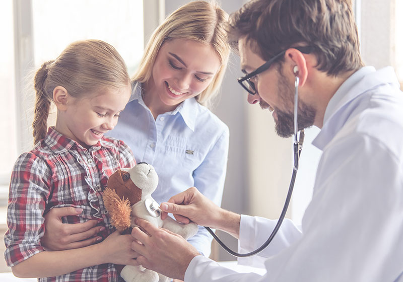 young blonde mum and daughter play with male doctor and stuffed toy