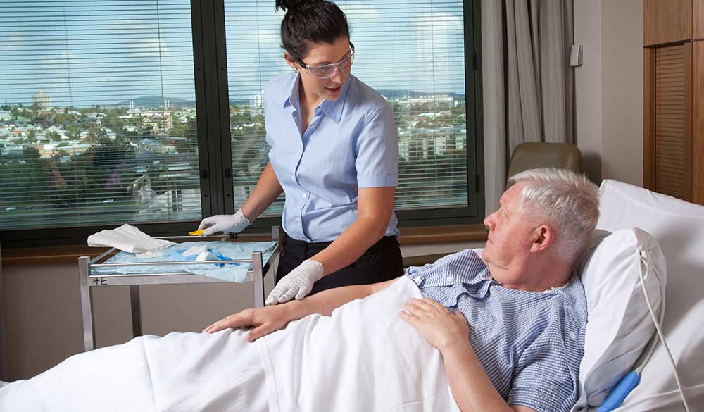 older man in hospital bed talking to woman doctor by his bedside