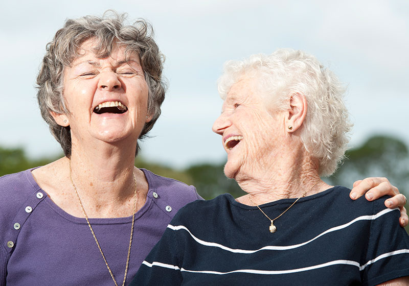two elderly women laughing together in the sun