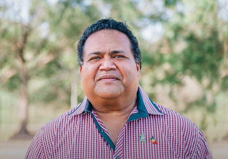 an indigenous man in a pink button up standing outdoors
