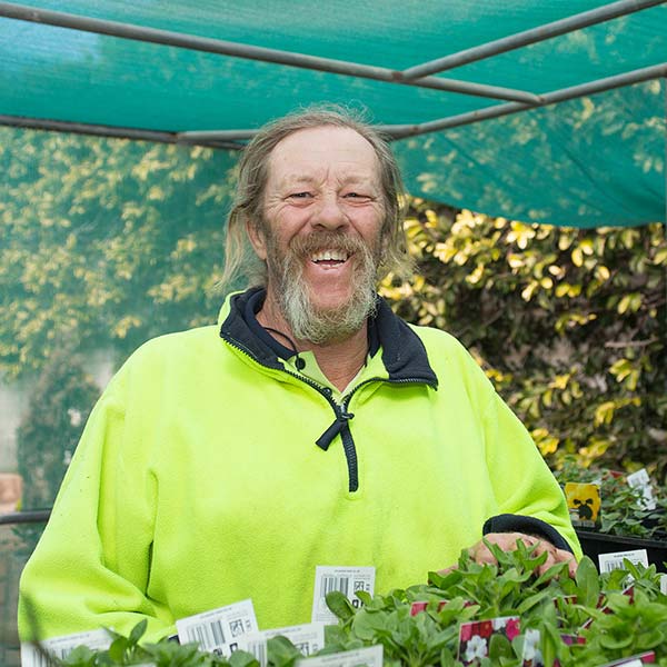 man with long grey beard in bright yellow jumper smiling outside