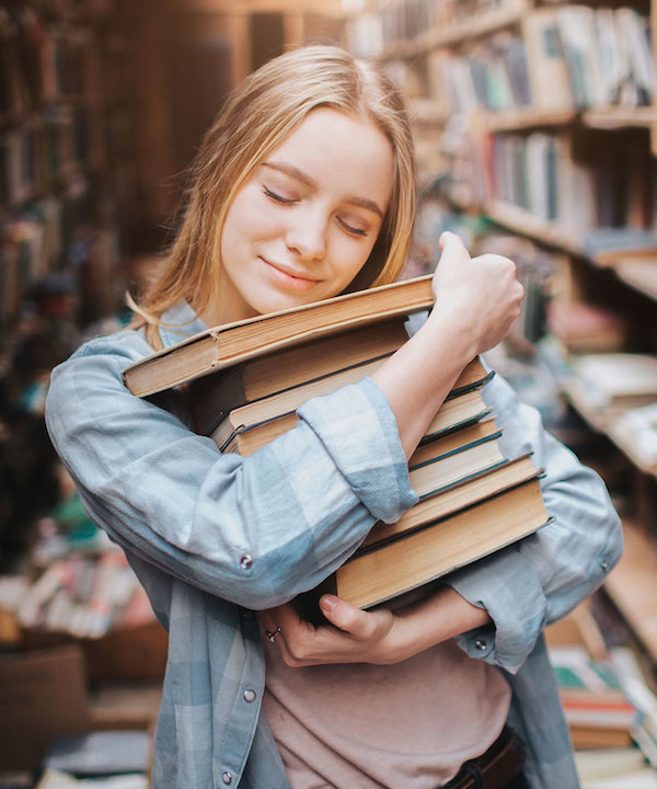 teenage girl hugging a stack of books
