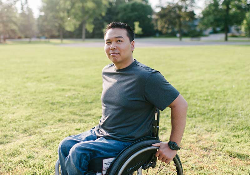man in a wheelchair outdoors in an open park