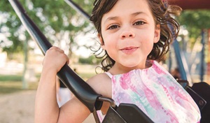 happy girl with pink dress on swing in the sun