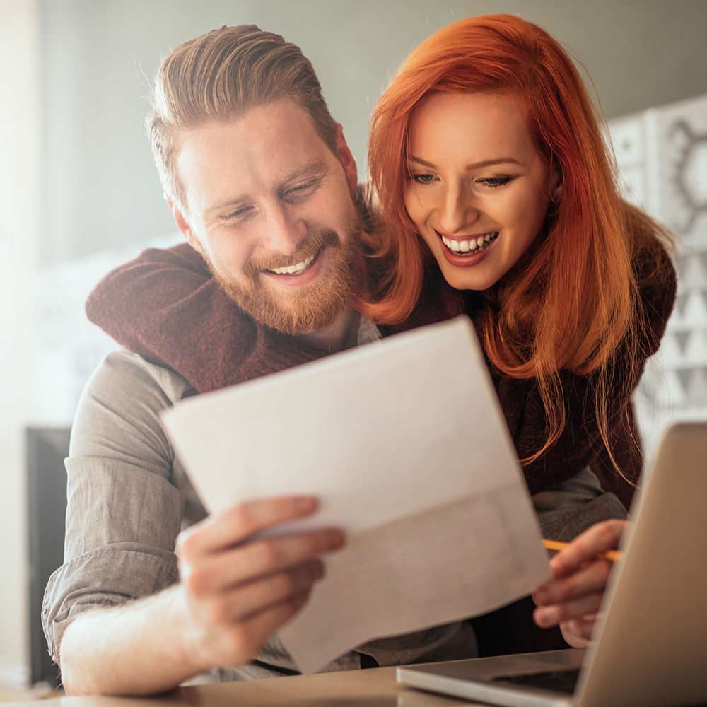red headed couple happily reading a letter