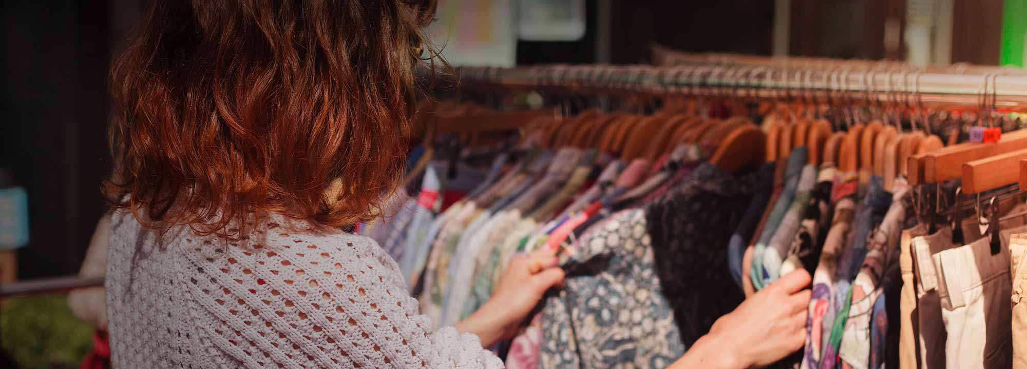 lady looking through a rack of clothing inside a store