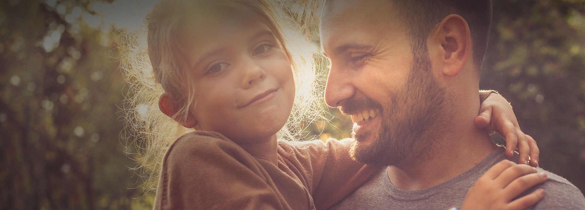 smiling father holding his young daughter looking to the camera