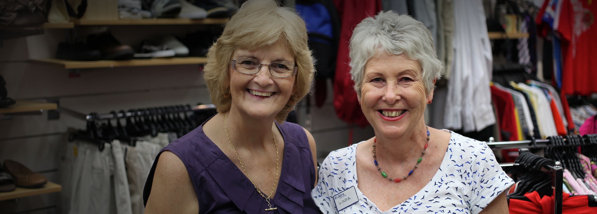 two elderly ladies standing next to each other smiling inside of a store