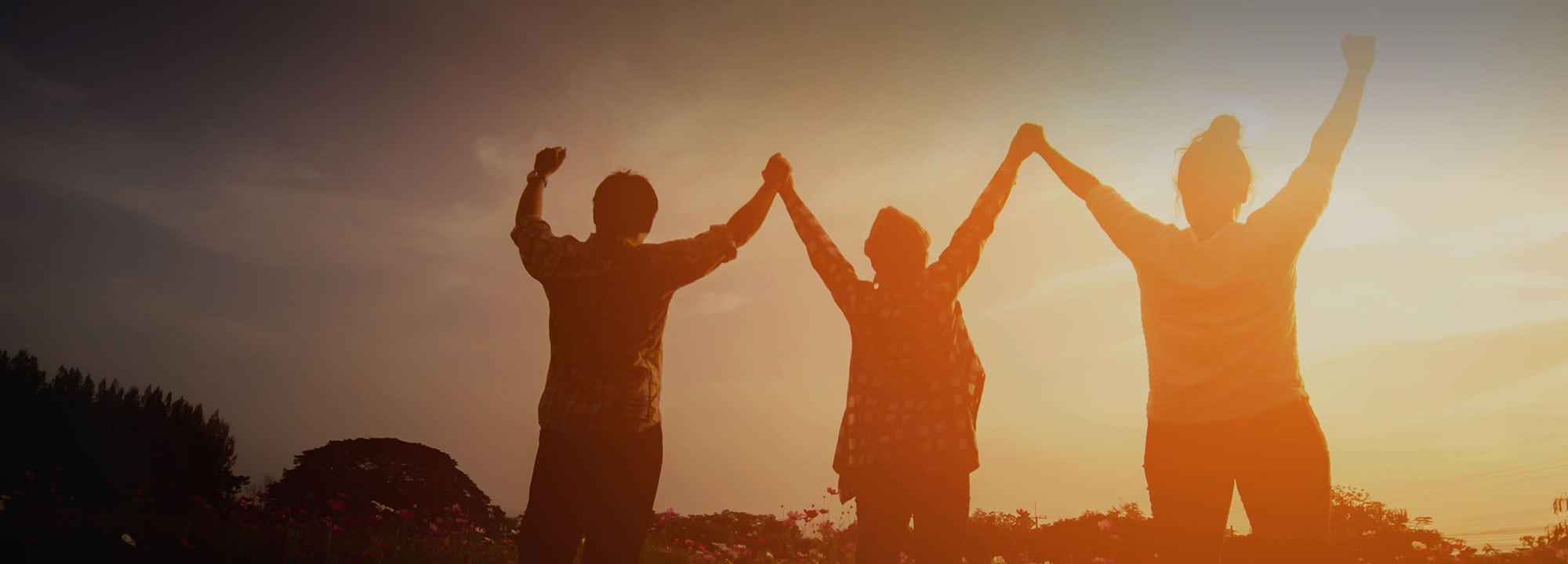 three people with their hands joined and raised over their heads outside