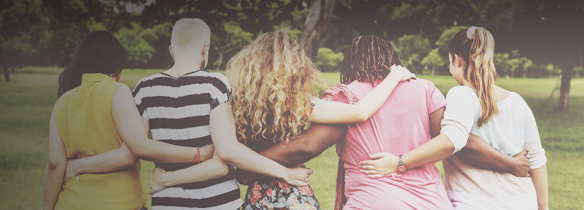 five ladies outside with their arms around one another's shoulders