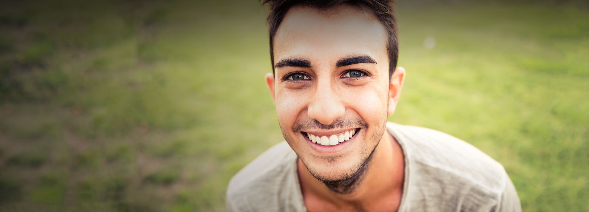 young man sitting outdoors smiling