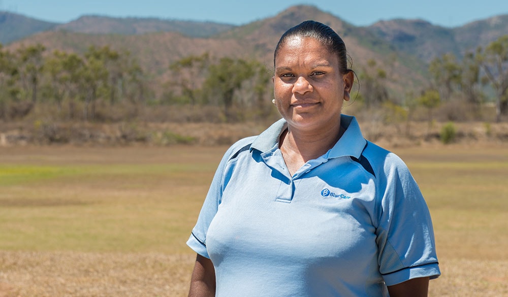 female staff member smiling outdoors with mountains in the background