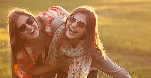 two young women outdoors embracing and smiling