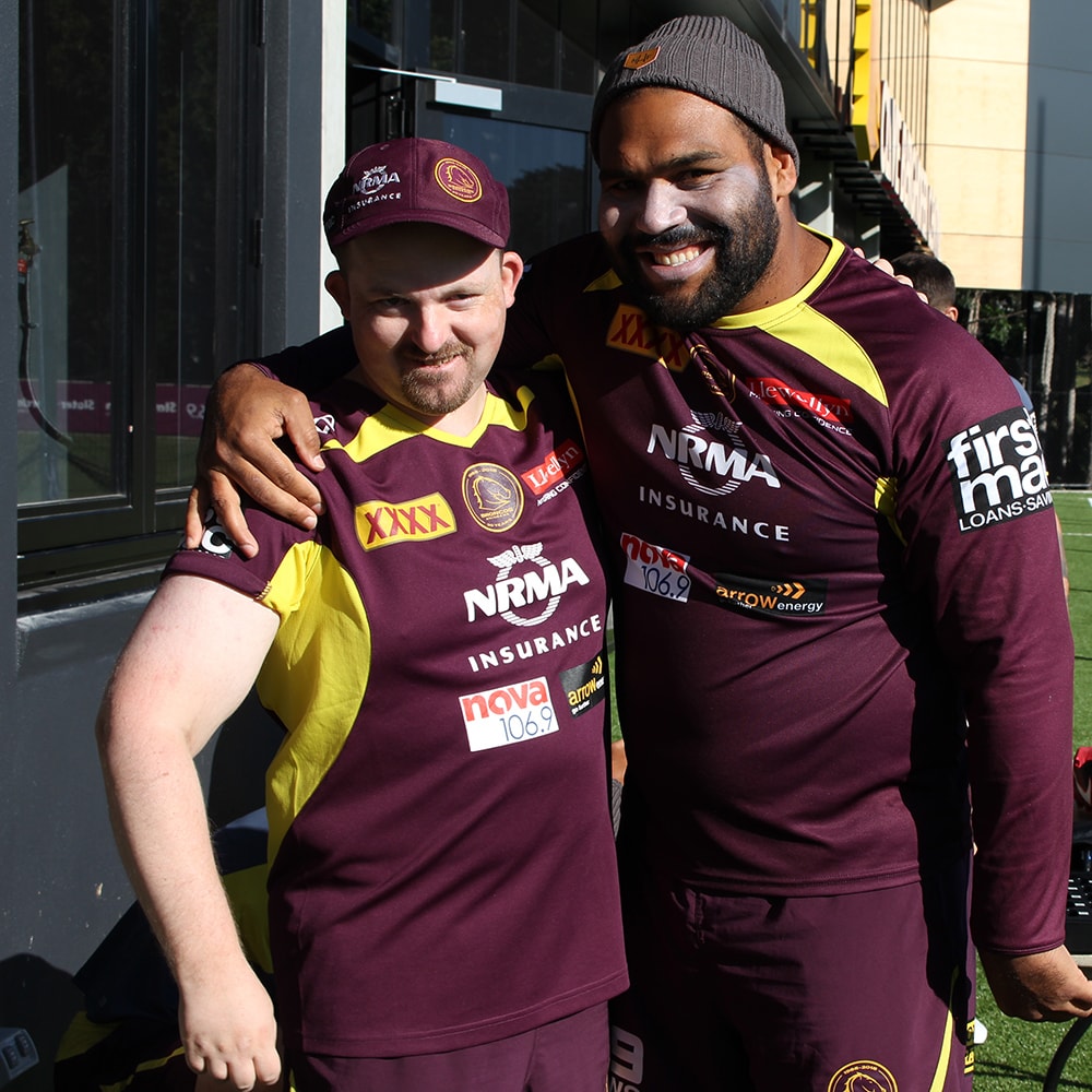 disabled man embracing sam thaiday on a football field