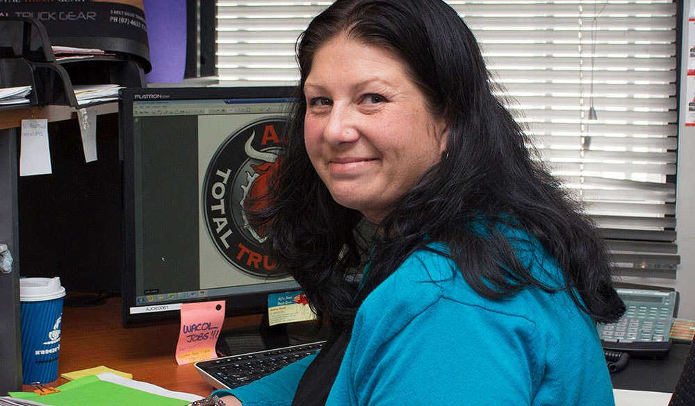 female staff member sitting at her desk smiling