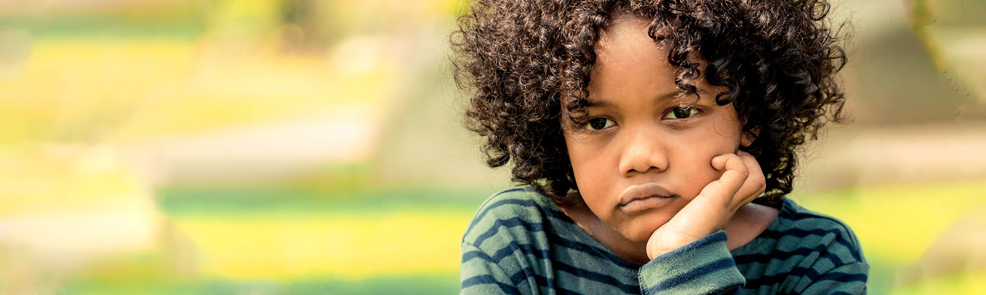 A child rests his face in his hands, looking troubled.
