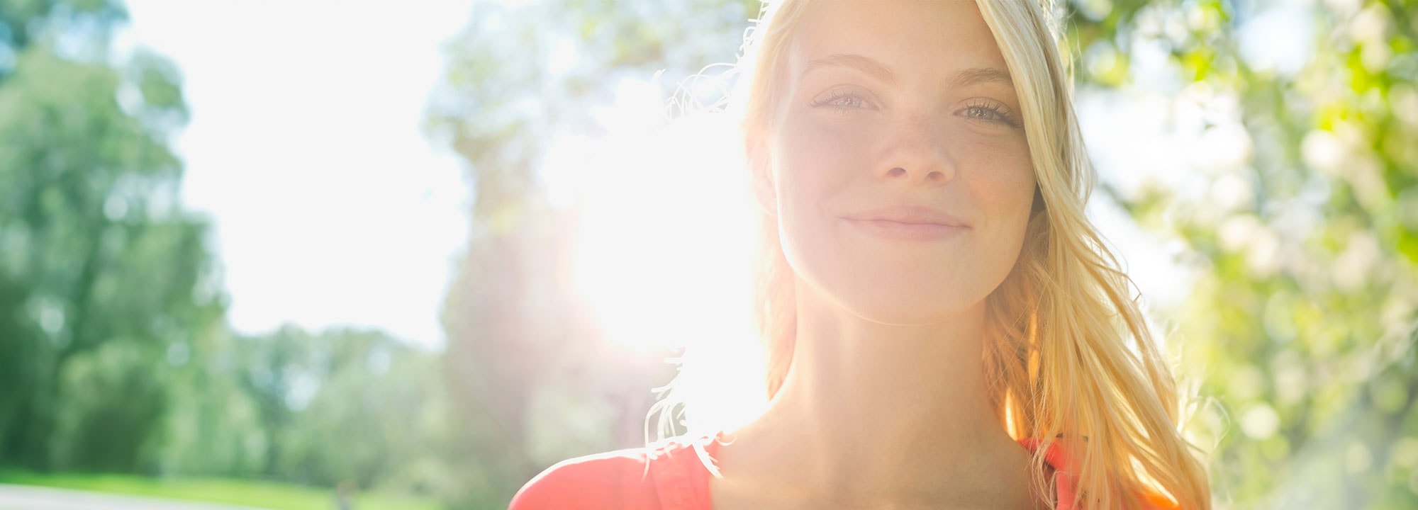 A young blonde woman smiling in front of a sunset
