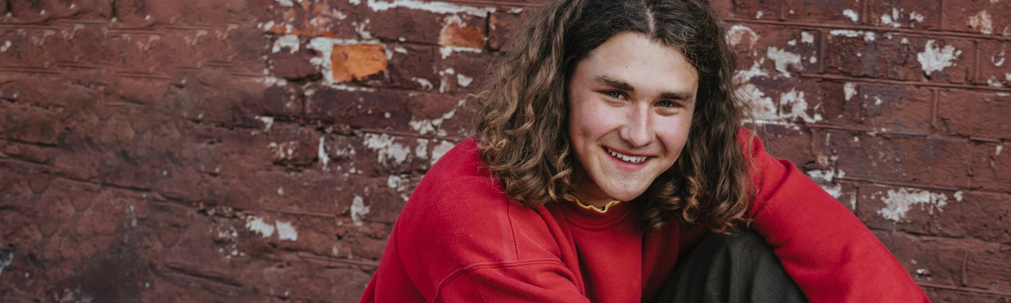 A smiling young man with long brown hair.