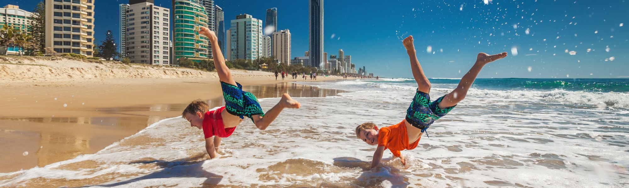 Two kids do handstands in the surf at the Gold Coast.