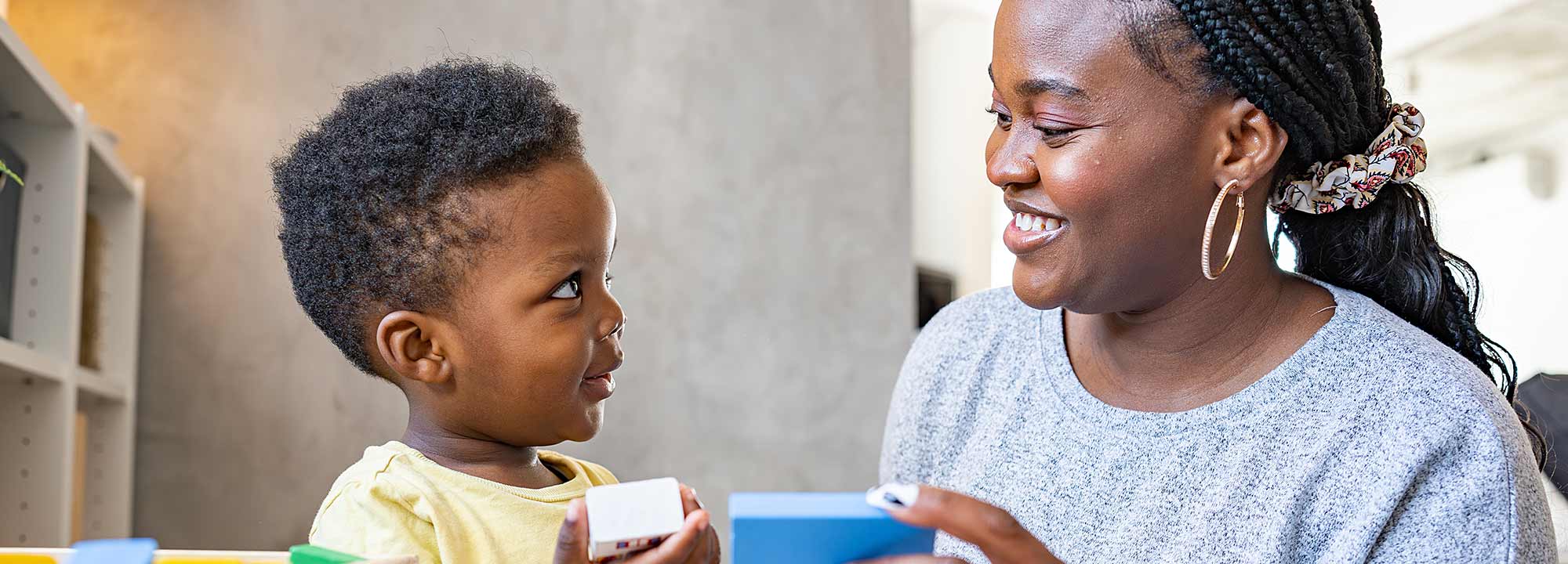 A young boy plays blocks with his mum