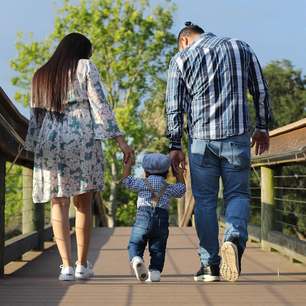 Adults holdings hand with a child walking along a boardwalk