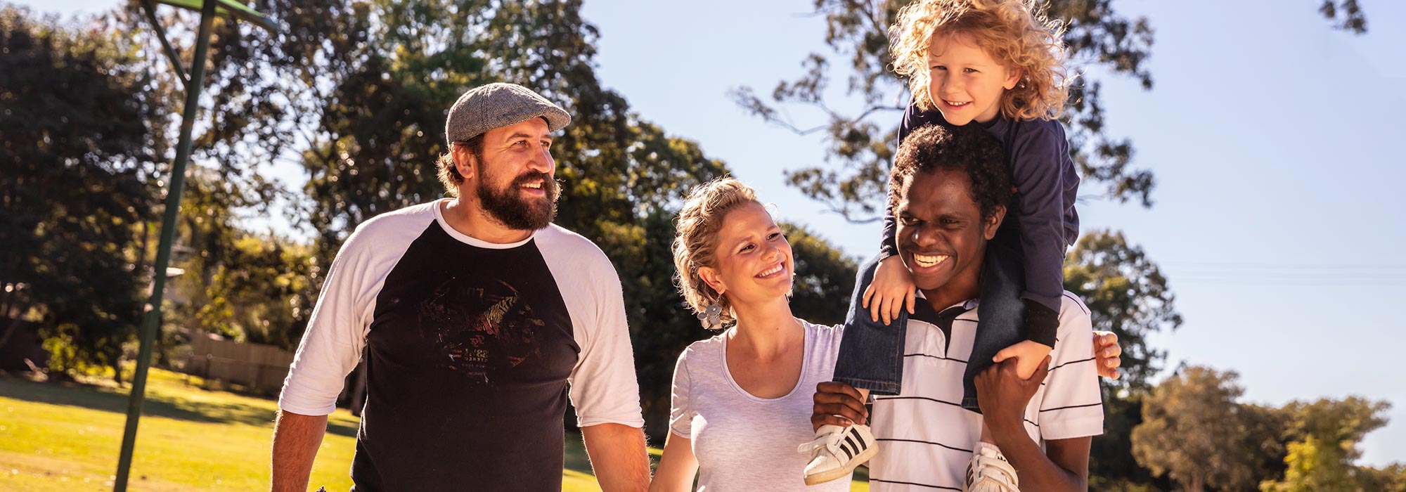 Multicultural family walking together through park and smiling