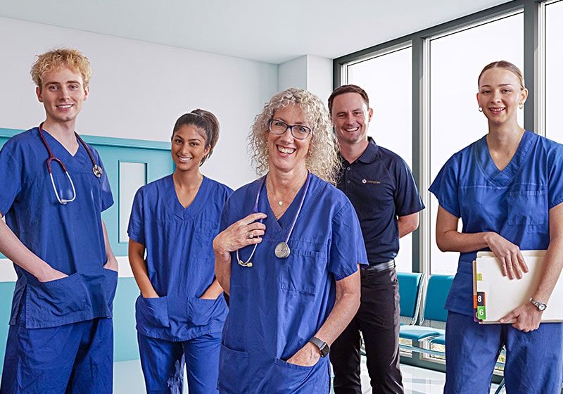 A group of graduate nurses stand in a hospital corridor.