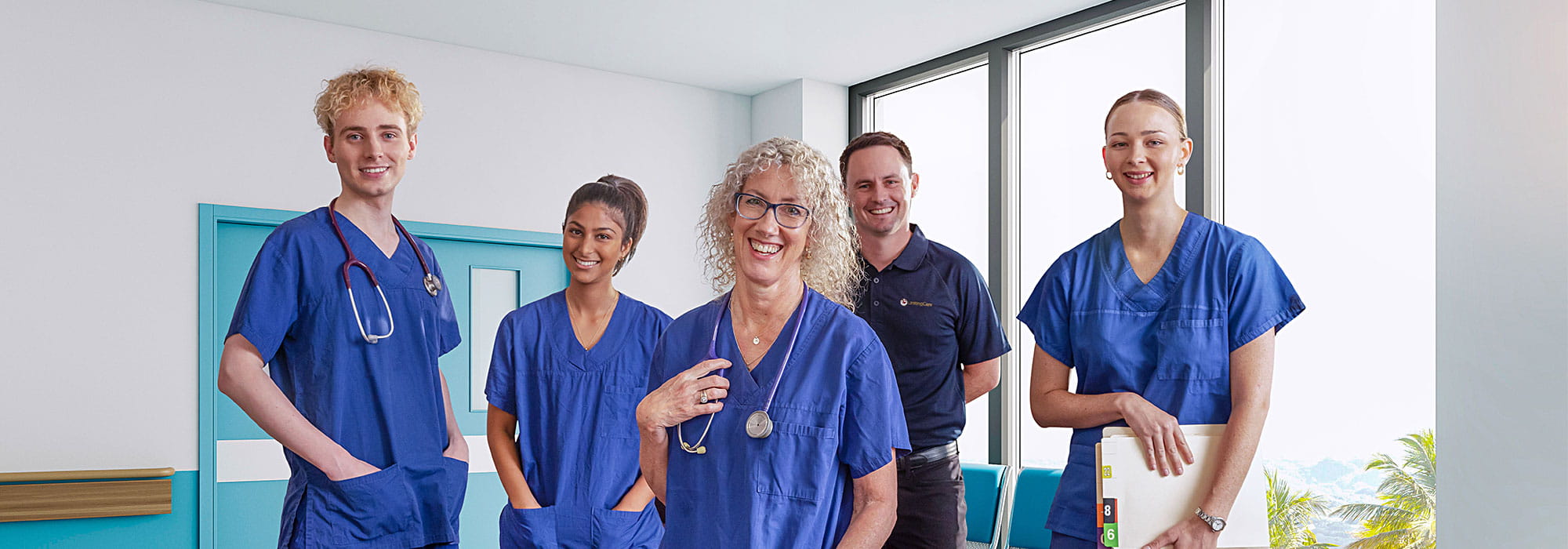 A group of graduate nurses stand in a hospital corridor.